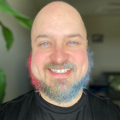 Picture of John Ambrose smiling with a mutli-colorbeard